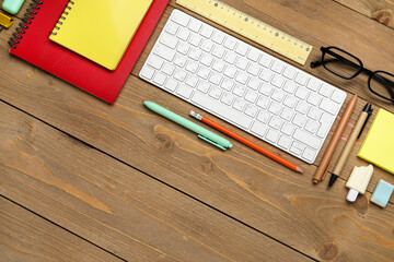 Composition with computer keyboard, eyeglasses and school supplies on wooden background, closeup