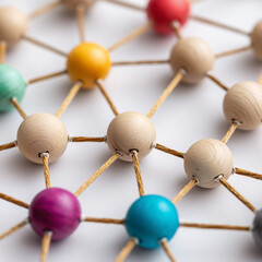 Colorful strings connecting light brown wooden beads on white background, abstract design representing network connections, collaboration, communication, innovation 