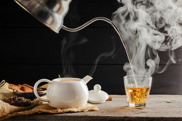 Hot tea is poured into glasses with steam. Teacups are placed on the table in the warm atmosphere of morning sunlight.