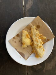 Crispy golden fried plantains served on a white plate atop rustic wooden table
