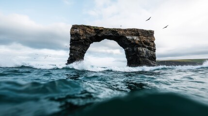 Majestic Natural Arch Overlooking Turquoise Ocean Waves Under Cloudy Sky in Remote Coastal Landscape