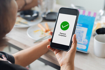 Woman use her smart phone to make a payment in a coffee shop by scan QR Code.