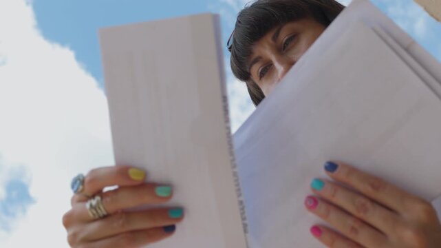 woman reading received letter standing among mailboxes. Portrait of smiling young woman opening mailbox studying received mail. girl with envelopes in hands.