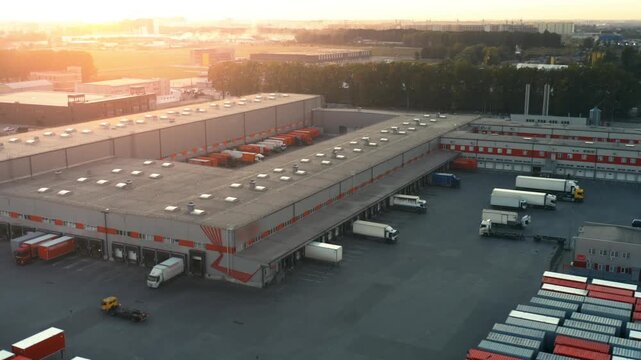 Logistics Distribution Center at Sunset | Aerial View of Modern Freight Hub with Loading Docks and Semi-Trailer Trucks | Industrial Supply Chain Operations Complex
