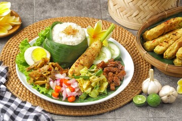 Nasi Campur Bali is a traditional Balinese dish consisting of warm white rice and various side dishes in small portions, such as shredded chicken, sate lilit, lawar, and sambal matah.