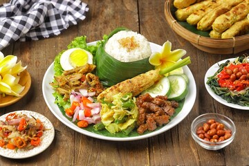 Nasi Campur Bali is a traditional Balinese dish consisting of warm white rice and various side dishes in small portions, such as shredded chicken, sate lilit, lawar, and sambal matah.