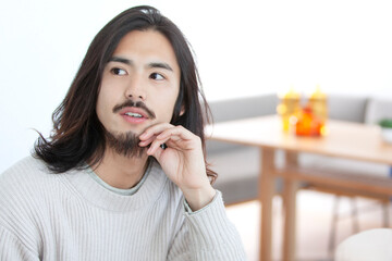 考え事をするロングヘアの男性