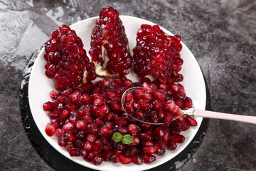 Fresh Red Pomegranate Arils and Segments on White Plate with Spoon - Healthy Mediterranean Fruit