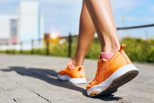 Female feet in sneakers walking on the sidewalk