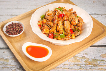 Spicy Bullfrog Stir-Fry with Peppers and Chili Oil on Wooden Serving Tray - Traditional Asian Cuisine