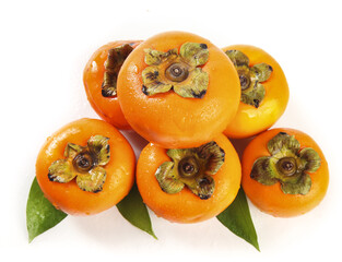 Fresh Orange Persimmons with Green Leaves on White Background - Sweet Seasonal Fruit Display