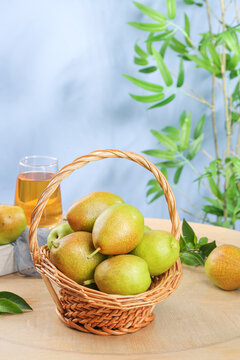 Fresh Organic Pears in Wicker Basket with Natural Light and Green Plants Background