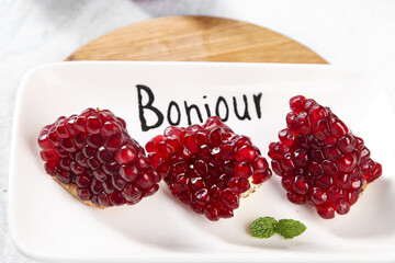 Fresh Pomegranate Seeds on Crackers with Bonjour French Text - Healthy Breakfast Snack © DangThi