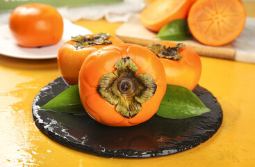 Fresh Ripe Persimmons on Slate Plate - Healthy Orange Autumn Fruit with Natural Leaves Display