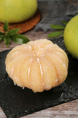 Fresh Peeled Pomelo Citrus Fruit Segments on Slate Board with Whole Fruits and Leaves