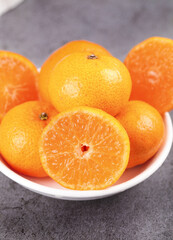 Fresh Sweet Little Tangerines and Oranges in White Bowl with Cut Half Showing Juicy Citrus Segments