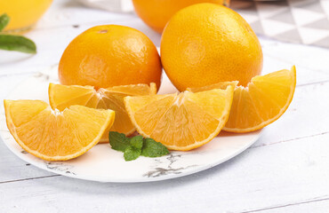 Fresh Orange Slices and Whole Oranges Display on Marble Plate with Mint Garnish