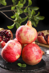 Fresh Ripe Pomegranates with Red Seeds on Dark Slate Surface