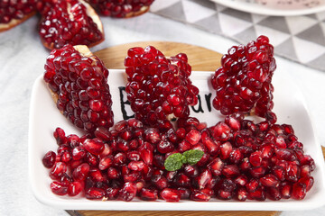 Fresh Red Pomegranate Seeds and Pulp with Pearl-Like Arils on White Plate