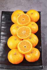 Fresh Small Oranges and Satsumas on Black Tray - Healthy Citrus Fruit Display