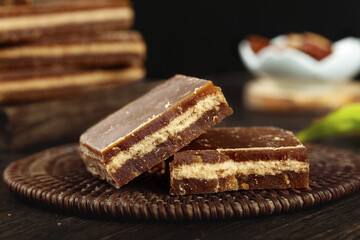 Handmade Brown Chocolate Layered Bars with Caramel Filling on Rustic Wicker Plate