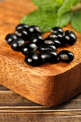 Fresh Black Beans on Wooden Board with Basil Leaves - Healthy Cooking Ingredients