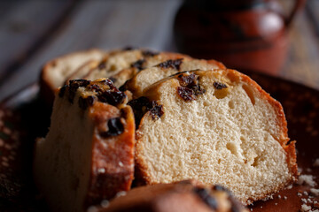 Mexican sweet bread with sliced ​​raisins with a handmade clay boorosa cup in the background, close-up photo or macro side view