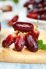 Fresh Red Finger Grapes from Yunnan on Wooden Board with Mint Garnish