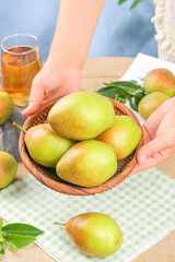 Fresh Ripe Mangoes in Wicker Basket with Hands on Kitchen Table - Healthy Tropical Fruit Concept