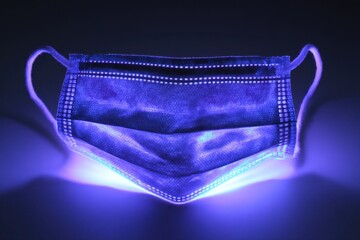 Ultraviolet Virus. Germ Detection on Medical Mask under UV Light for Covid-19 Hygiene