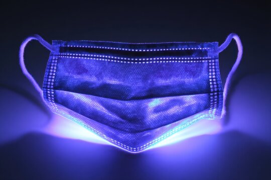 Ultraviolet Virus. Germ Detection on Medical Mask under UV Light for Covid-19 Hygiene