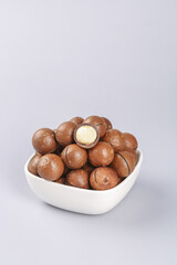Macadamia Nuts in White Bowl - Healthy Snack Arrangement with Cracked Nut Showing Interior