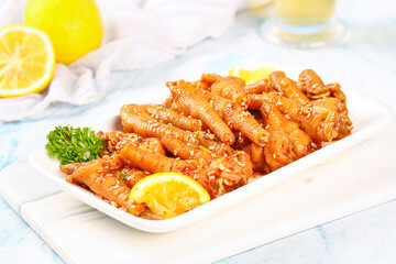 Glazed Chicken Feet with Lemon Garnish Traditional Asian Appetizer Dish on White Plate