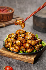 Fried Silkworm Pupae Asian Street Food Delicacy with Chopsticks on Wooden Board