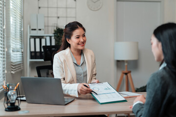 Businesswomen analyzing financial data and discussing charts during a productive meeting in a modern office