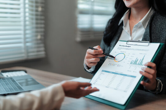 Businesswoman discussing positive monthly budget results with a colleague, highlighting growth and success through detailed financial analysis