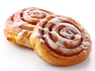 Fototapeta premium Two cinnamon rolls topped with sweet white icing, displayed on a white background