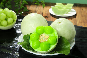 Fresh Jade Green Melon from Shandong China with Mint Leaves on Dark Slate Board