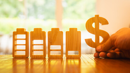 Wooden battery icons with decreasing levels beside a dollar sign represent energy consumption, cost...