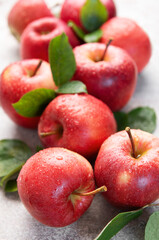 Fresh red apples with water drops and green leaves on gray background