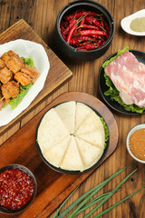 Korean BBQ spread with grilled pork belly, spicy peppers and traditional sides on wooden table