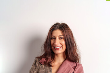 Fototapeta premium Professional businesswoman smiling, wearing pink brown jacket against white backdrop