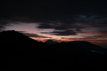Scenic view of mountain silhouettes at dusk with a colorful twilight sky and dramatic clouds. Beautiful natural landscape perfect for themes of travel, adventure, and nature scenery.