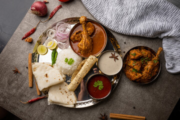 Kolhapuri chicken Thali is a popular Indian asian food platter consists of poultry meat, chikan sukka bhakri, rice, salad tambda padhra rassa 