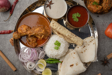 Kolhapuri chicken Thali is a popular Indian asian food platter consists of poultry meat, chikan sukka bhakri, rice, salad tambda padhra rassa 