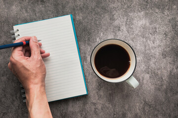 Hand writing on Notebook with Cup of Coffee on Table