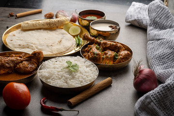 Kolhapuri chicken Thali is a popular Indian asian food platter consists of poultry meat, chikan sukka bhakri, rice, salad tambda padhra rassa 