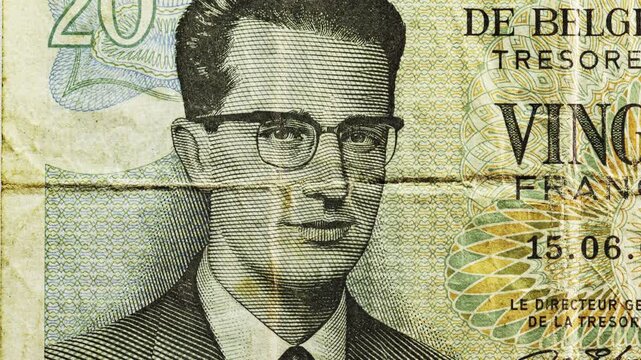 Macro pan of Belgian 20 francs note showing portrait, French text and a heavy center crease