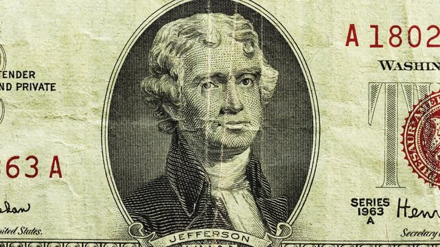 Close pan of a worn 1963 U.S. two dollar note with red seal, visible creases and aged paper