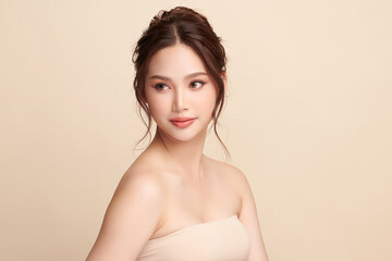 Obraz premium A beautiful young Asian woman with clean, fresh skin against a beige background. Skincare, facial treatment, cosmetology, beauty, and spa. An elegant portrait of an Asian woman.